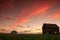 Sunset and a couple abandoned and broken down farm house in the Alberta prairies