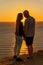 At sunset, a couple shares a tender embrace on the beach, basking in the tranquility of their holiday and the beauty of