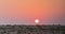 Sunset in desert, sun sets over the horizon or hill, orange sky, dusk