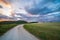 Sunset dramatic sky over country road in Marche region, Italy. Epic clouds above winding trail unique hills and mountains