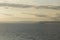 Sunset dusk seascape view of a lonely boat on calm water, with beautiful clouds, islands and islets on a soft yellow sky and white