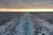Sunset at the end of water mark left after sailing cargo ship.