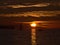 Sunset at English Bay in Vancouver, Canada with sun disappearing behind the mountains of Vancouver Island and sailing boats.