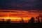 Sunset in the field near the road. Orange fiery sunset behind