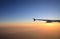 Sunset flight view with airplane wing silhouette