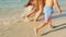 At sunset, happy family mom, dad and baby. running barefoot on wet sand. sea surf, close-up of feet. footprints in the