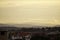 Sunset in a hilly city, silhouettes of mountains on the horizon, layered clouds and the sun. top view of the city, forests