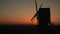 Sunset on the horizon behind a windmill at dusk