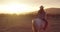 Sunset, horse riding or woman in countryside outdoor with rider or jockey for adventure or wellness. Travel, back view