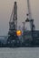 SUNSET WITH INDUSTRIAL SHIPYARD CRANES IN DUSK