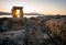 Sunset through Inuksuk in rough arctic landscape. Sunstar on the horizon in the fjord of Qikiqtarjuaq, Broughton Island