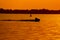 Sunset on lake or river, dense forest on the horizon. Jet ski passing over the water