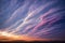 a sunset with a large cloud formation in the sky above a field of grass and trees in the distance