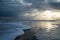 Sunset with Light Beams over the Ocean with Foamy Waves on the Beach