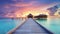 Sunset on Maldives island, luxury water villas resort and wooden pier. Beautiful sky and clouds and beach background for summer