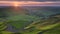 Sunset at Mam Tor, Peak District National Park, with a view along the winding road among the green hills down to