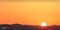 Sunset and mountains background. Realistic dawn wallpaper. Beautiful orange sky with bright sun.