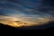 Sunset in a mystic scenery with colorful sunset with different types of clouds and a hill silhouette in austrian alps in styria