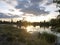 Sunset in nature, the river, the shore in the green, clouds.