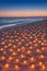 Sunset ocean sandy beach decorated with lot flare lights of candles. Romantic sea vacation or honeymoon concept vertical