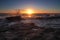 Sunset with orange clouds and spray from waves crashing onto rocks at Dunraven Bay, Vale of Glamorgan, South Wales