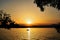 Sunset on an orange-gold sky, a boat floating in the water