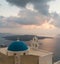 Sunset over aegean sea with view to Virgin Mary Catholic Church Three Bells of Fira, Santorini.