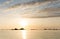 Sunset over a calm ocean with rocks and reefs in silhouette