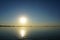 Sunset over the calm surface of the lake and beautiful glare of the sun on the water