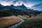 Sunset over Claree Valley with Main De Crepin peak and river flow through in larch forest during autumn at French Alps, France