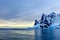 Sunset over cliffs, blue glacier and drifting iceberg with water