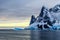 Sunset over cliffs, blue glacier and drifting iceberg with water