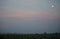 Sunset over corn field with moon in right corner