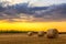 Sunset over farm field with hay bales