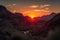 sunset over fiery canyon with silhouette of rugged mountain range in the background