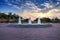 Sunset over a fountain with three sprays in a reflective pool