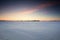 Sunset over a frozen snow covered field.