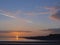 Sunset over Galway bay, Ireland, Calm cloudy sky, Sun reflection. Town skyline silhouette