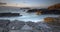 Sunset over Godrevy Lighthouse on Godrevy Island in St Ives Bay with the beach and rocks in foreground, Cornwall uk