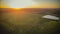 sunset over a green field and a lake. aero photo