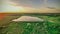 sunset over a green field and a lake. aero photo