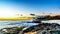 Sunset over the horizon with a few clouds and the rocky shores of the west coast of Oahu