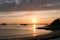 Sunset over an idyllic bay and beach with a view of the ocean and rocky reefs under a colorful sky