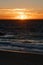 Sunset over the Indian Ocean in City Beach in Perth with silhouettes of swimmers and surfers in the ocean water