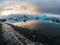 Sunset over Jokulsarlon glacier lagoon in Iceland, golden colors reflect on the water and contrast with the blue icebergs