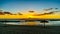 Sunset over the lagoon and beach with thatched umbrellas under blue sky on the West Coast of Oahu