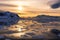 Sunset over the lagoon with drifting icebergs and snow mountains