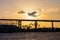 Sunset over lagoon with silhouette of bridge and palm tress