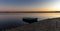 Sunset over Lake Budeasa in central Romania with a wooden rowboat tied up on the rocky beach