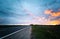 Sunset over the meadows near the highway. Summer landscape with beautiful sky